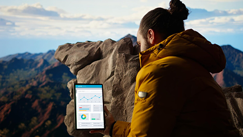 SEO consultant viewing analytics on tablet atop mountain.